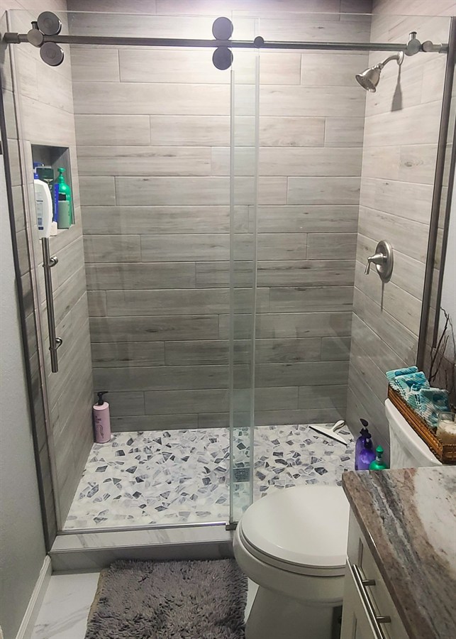Wood-look plank tile shower with terrazzo mosaic floor