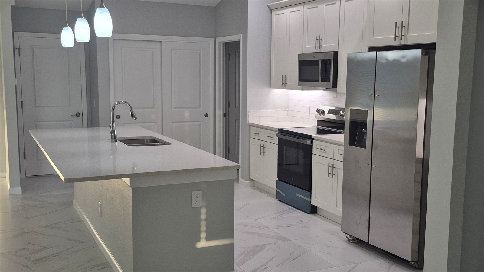 White kitchen with tile backsplash and marble-look tile flooring