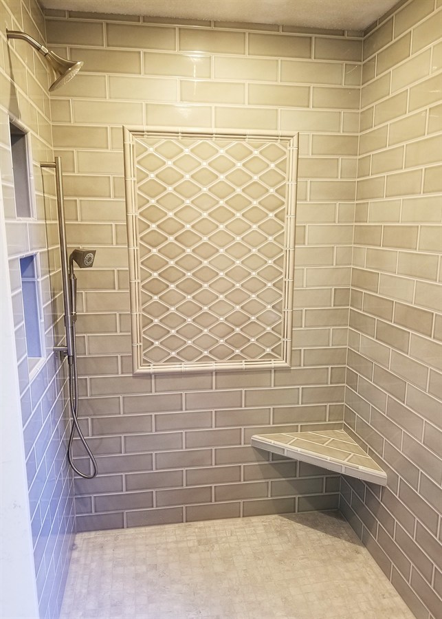 Subway tile shower with mosaic inset accent panel and corner bench