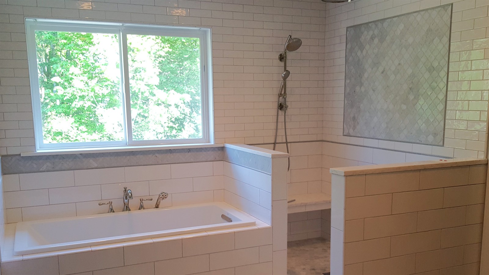 White subway tile shower with marble arabesque accent tile